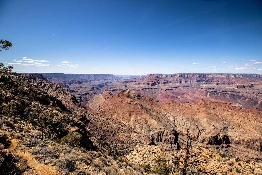 A spectacular view of the Grand Canyon from above, with the red rocks contasting the blue sky.