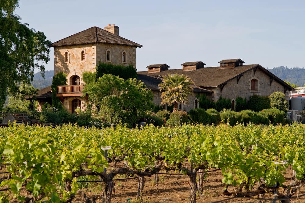 A gorgeous winery in Napa Valley, Califonia with stone buildings and lush greenery