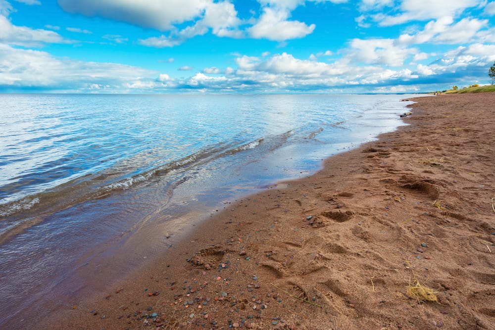 The grainy brown sand and blue water of Lake Superior in Duluth, Minnesota.