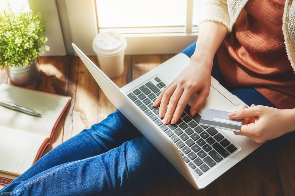 Women holding a credit card and using It to file a claim on a laptop, which is what to do if your luggage is lost.