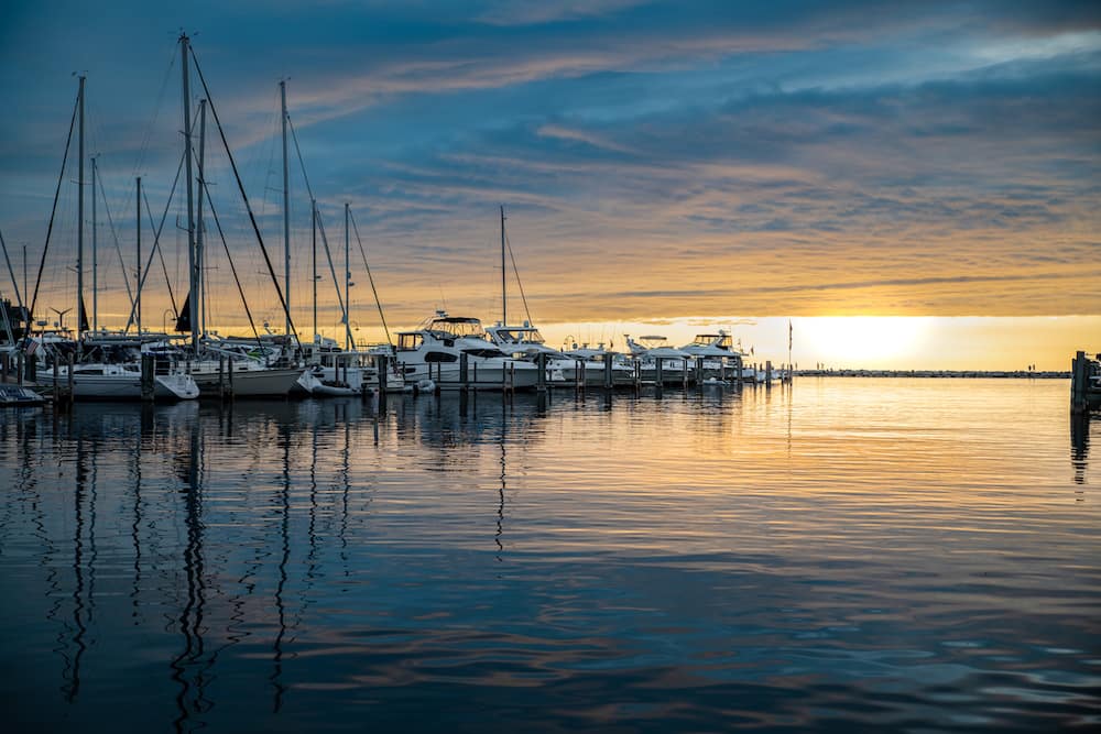 Several boats sitting on the water at sunset in Petoskey, Michigan.