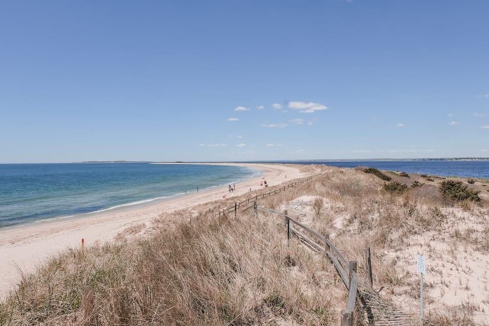 A sandy beach with blue waters in Westerly, Rhode Island, one of the best places to visit in the USA in August.