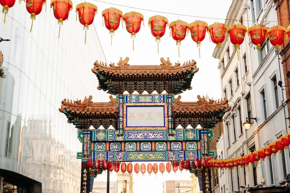 The colorful entrance to Chinatown in London with red lanterns strung above the street.