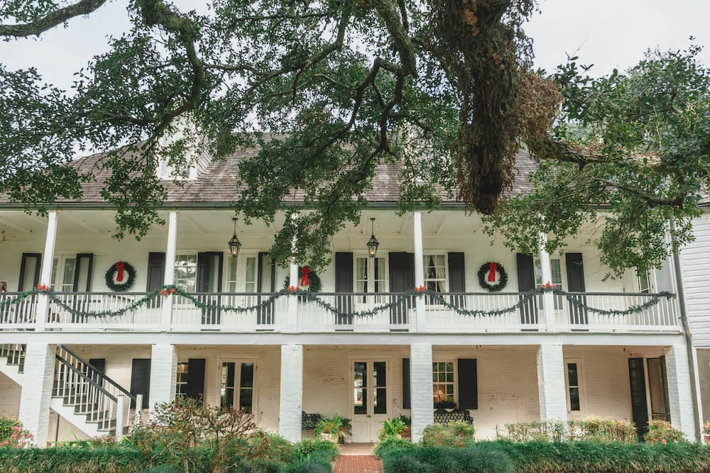 A cute white house decorated for the holidays with wreaths, garland, and red bows in Natchitoches, Louisiana