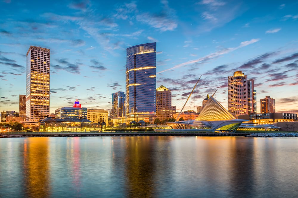 Milwaukee, Wisconsin, USA – downtown city skyline with city lights on Lake Michigan at twilight.