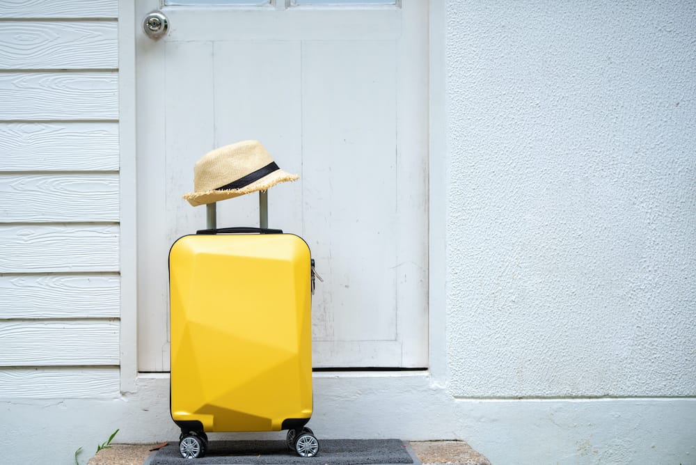 Yellow suitcase and hat sitting in front of a door