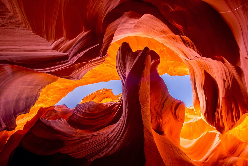 The bright red slot canyon of Antelope Canyon in Arizona framing the blue sky behind the canyon.