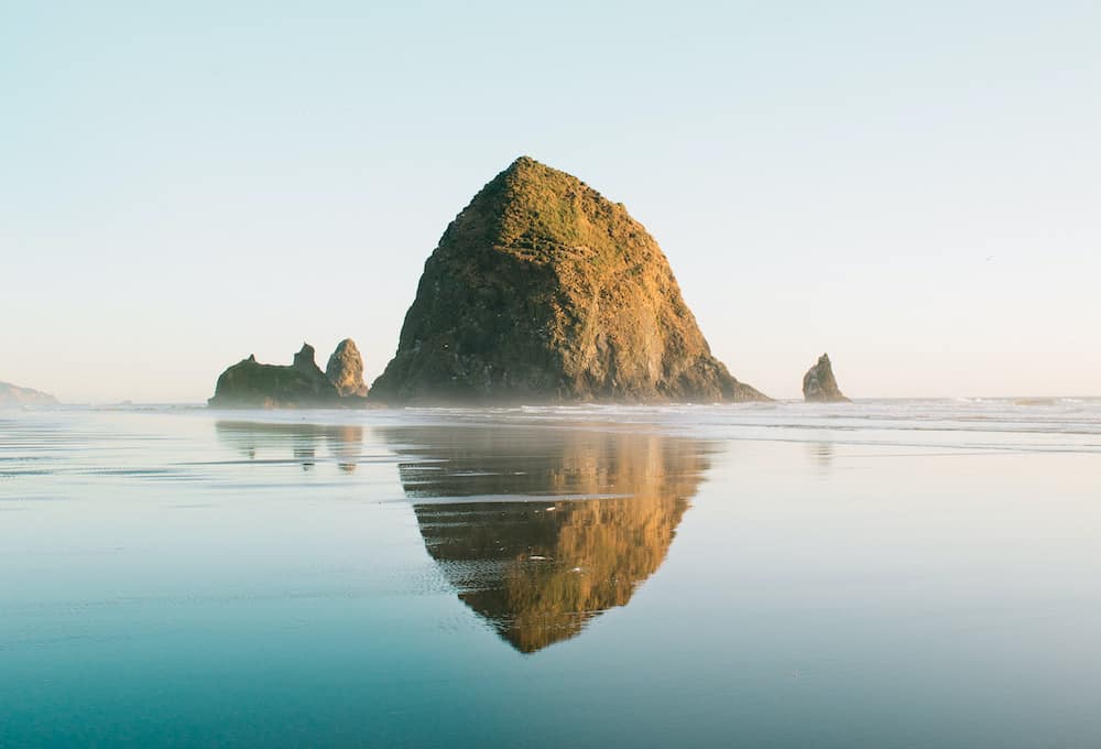 Haystack Rock sitting in the ocean on a misty morning on Cannon Beach.