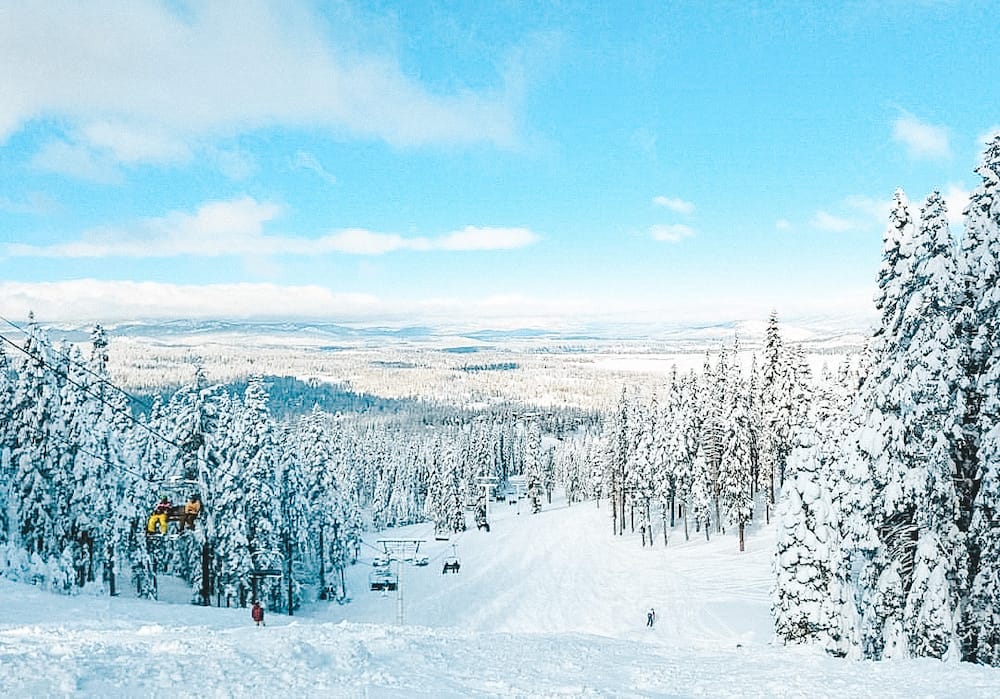 A ski lift, pine trees covered in snow, and a snowy slope downhill at Lake Tahoe in January.