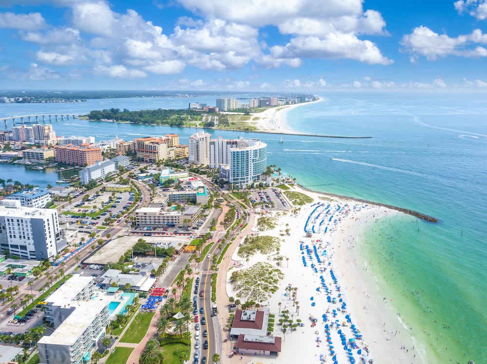 An aerial view of the hotels, blue umbrellas, white sand and turquoise water at Clearwater Beach.