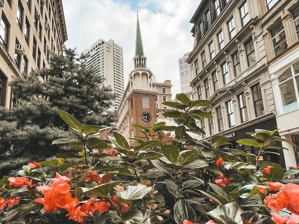 The Old South Meeting House with red flowers and greenery in the foreground in Boston - one of the best places to visit in the USA in March.