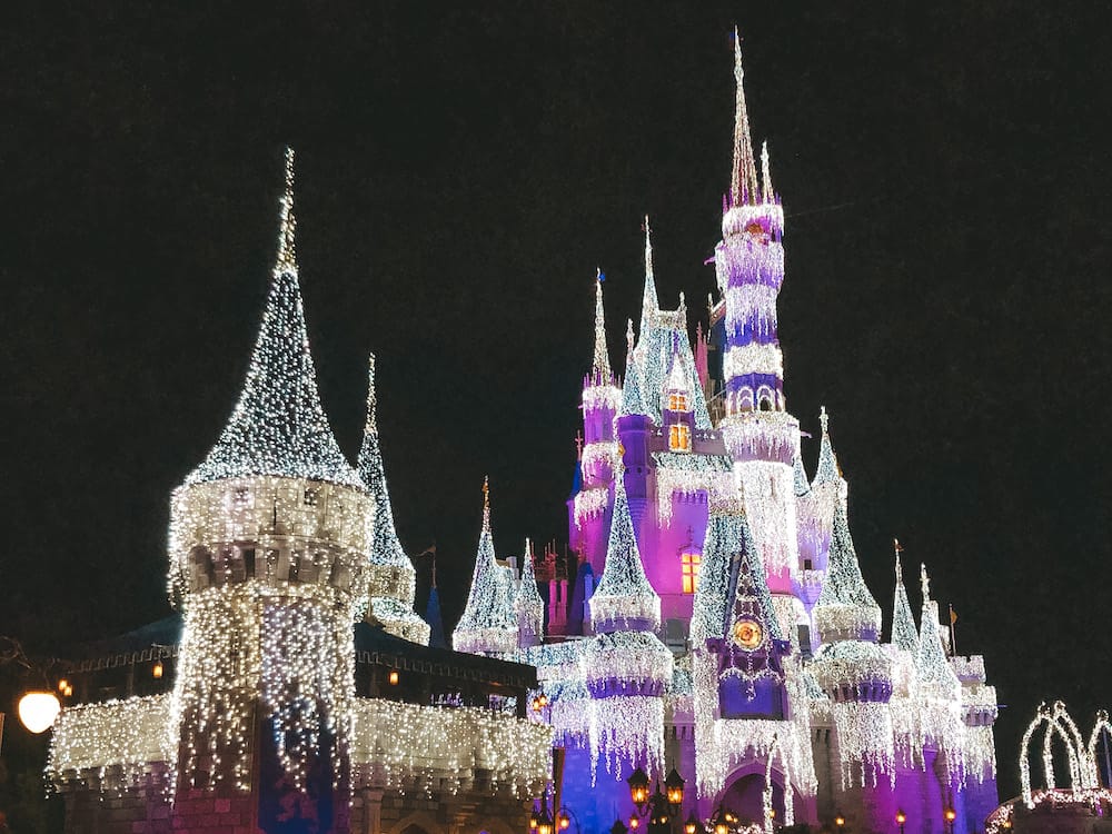 The Disney World castle covered in Christmas lights during the months of November and December