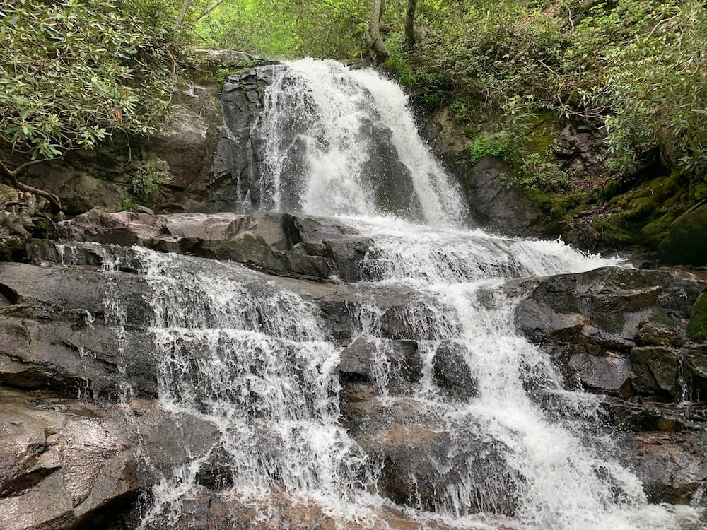 A tumbling waterfall in the Smoky Mountains National Park falling onto rocks and surrounded by greenery