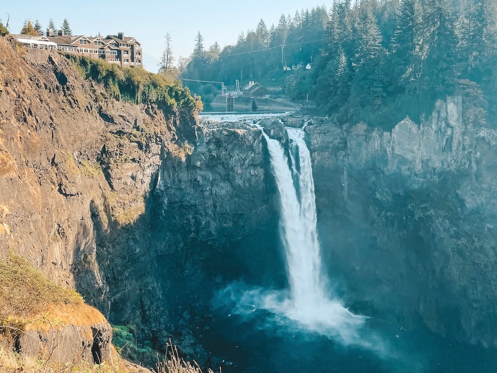 A massive waterfall cascading off a rocky cliff with a hotel overlooking the falls.