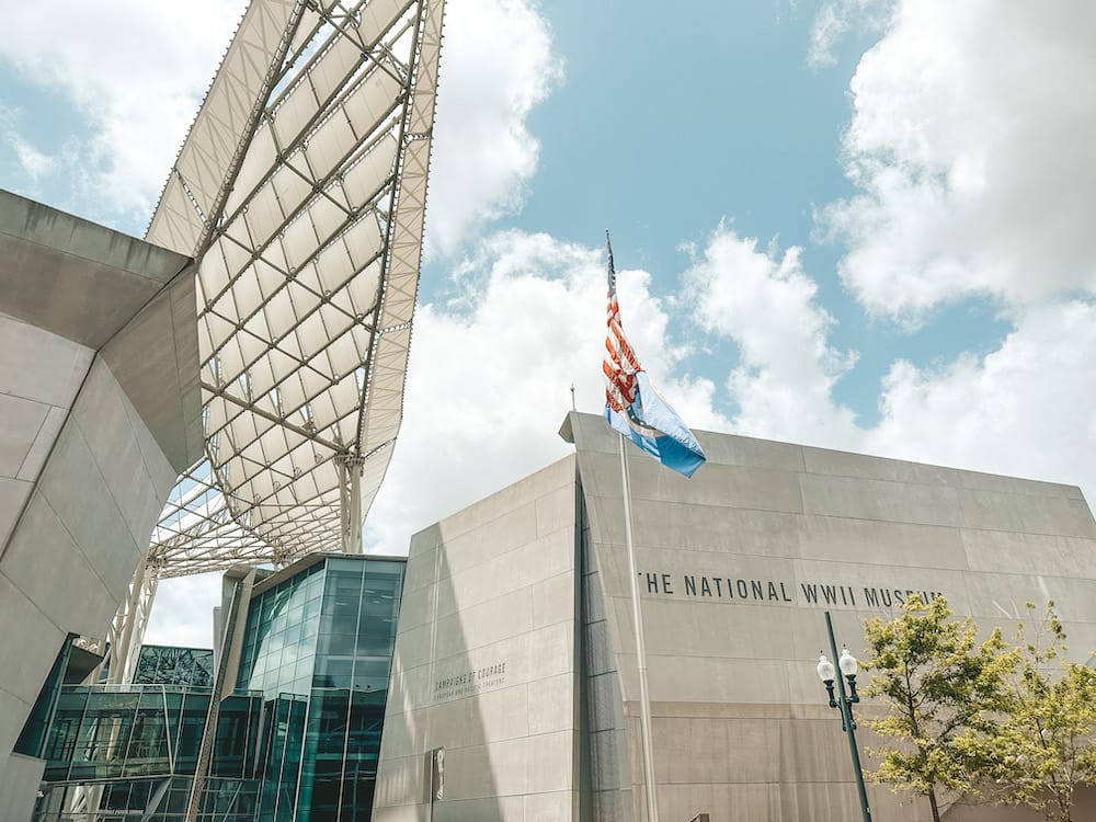 The outside of The National WWII Museum in New Orleans, with two flags waving in front of the building.