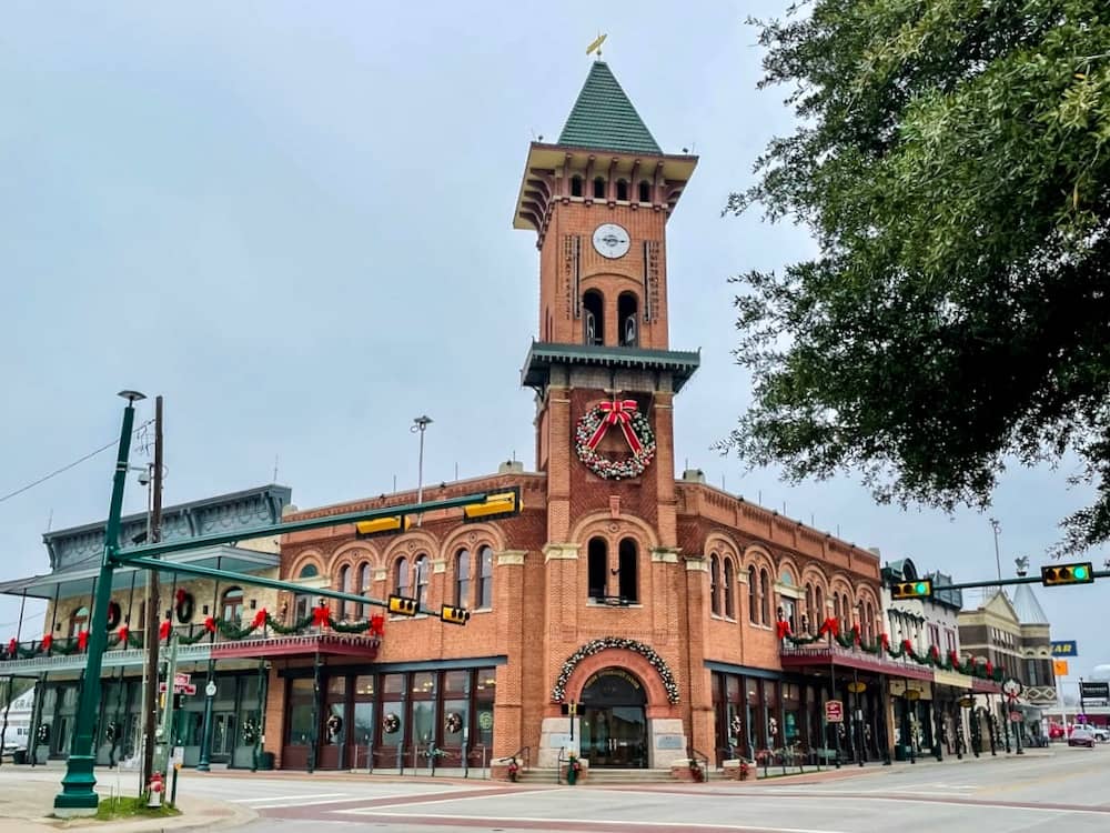 A historic red brick building in Grapevine, Texas, decked out in a holiday wreath, garland, and red bows.