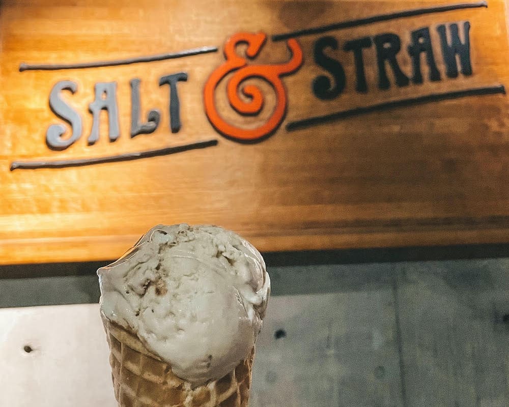 An ice cream cone in front of the Salt & Straw sign.