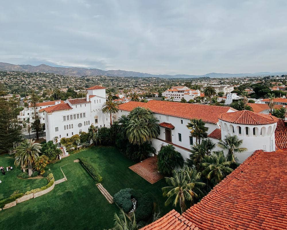 Several Spanish-style orange and white buildings surrounding a lush green courtyard in Santa Barbara, California.