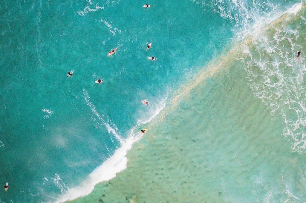 Several surfers float in the waves during the Pipeline Pro Surf Competition on the North Shore, one of the best free things to do in Oahu.