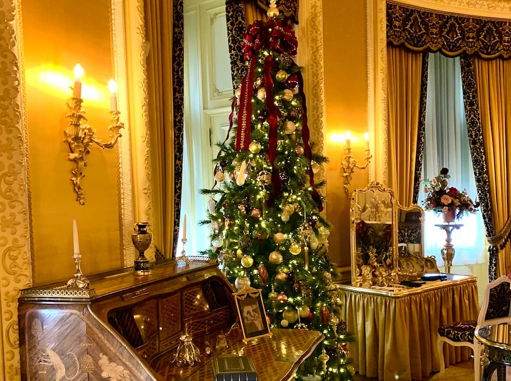 A Christmas display inside the Biltmore Estate in Asheville, NC, surrounded by historic furniture, like a vanity and writing desk.