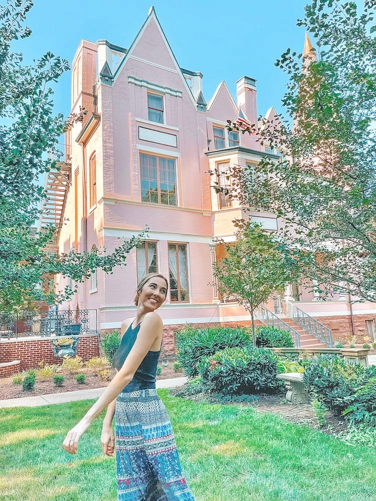 Weekend in Louisville - Woman twirling in front of large pink Victorian-style house - Travel by Brit