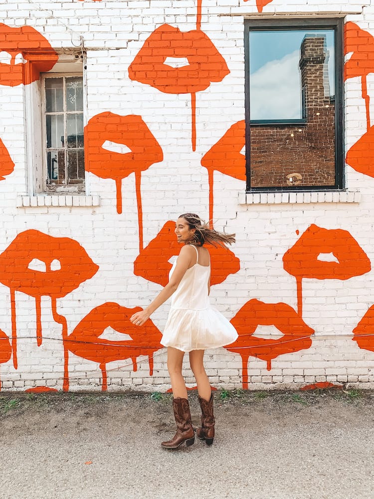 A white wall with tons of drippy red lips painted in it