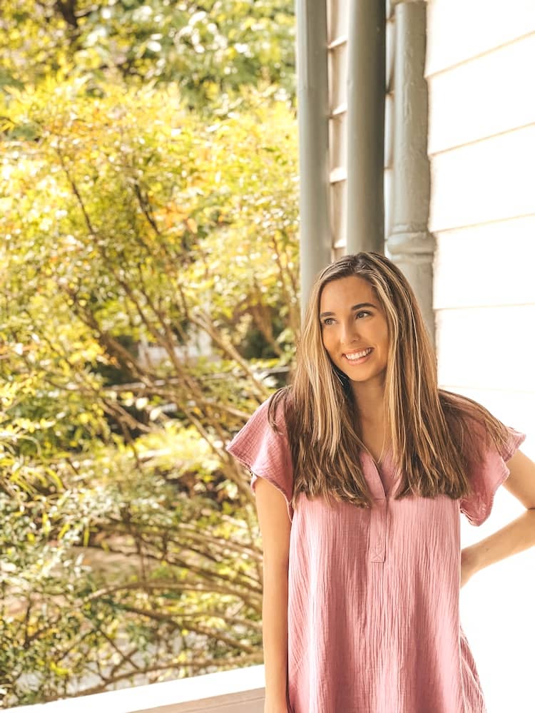 Travel by Brit standing in a pink dress on the porch of Biscuit Love, one of the best places to eat in Franklin, TN
