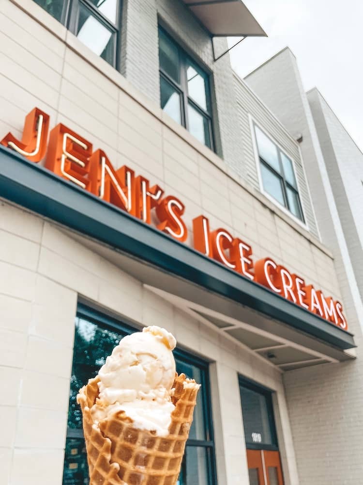 An ice cream cone held in front of the Jeni’s Ice Creams sign in Nashville
