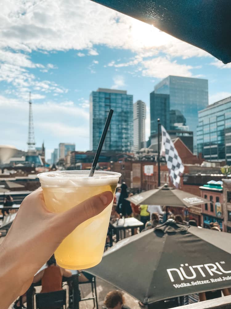 A margarita held against the sky and cityscape from a rooftop bar in Nashville, TN