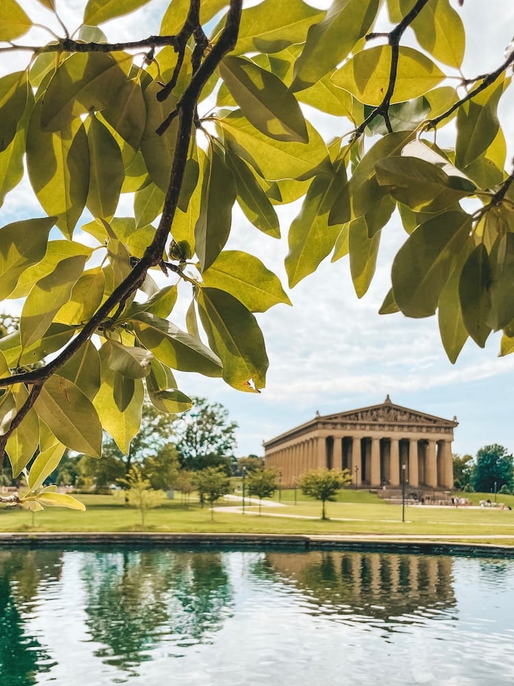 The Parthenon Replica is one of the best things to do in Centennial Park Nashville, sitting behind a tree and a lake.