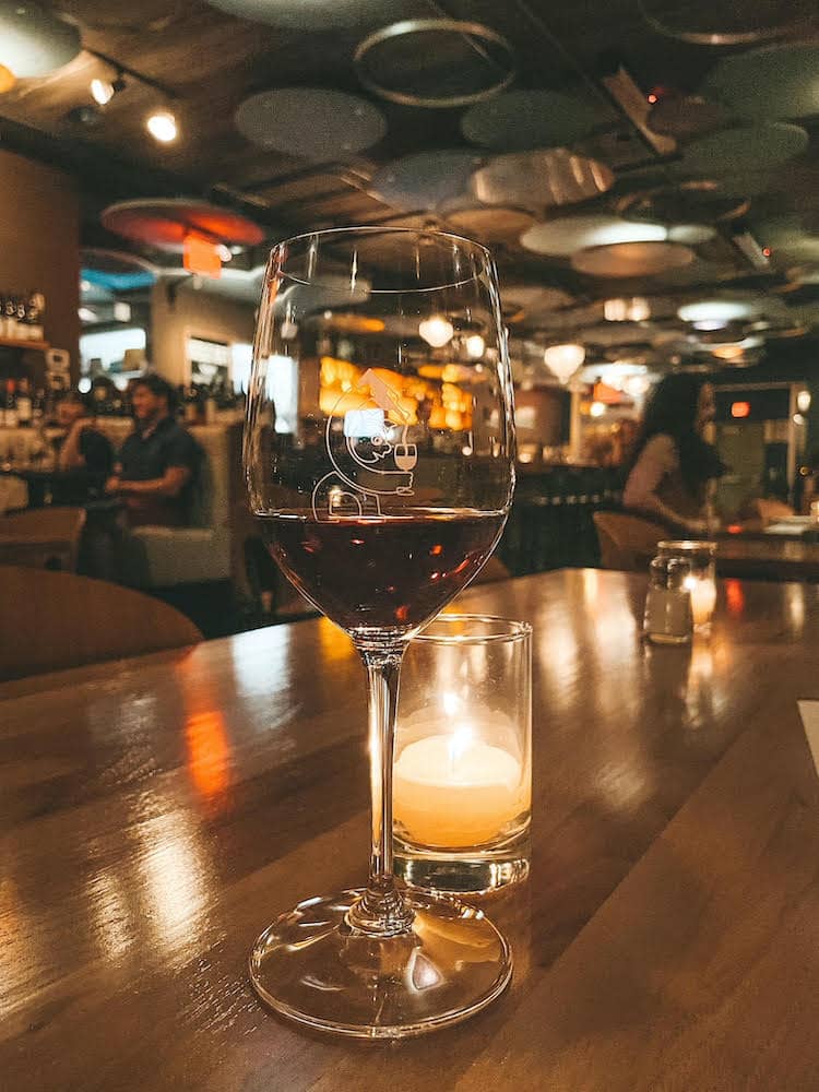 A glass of wine sitting on a table in front of a candle in Portland.