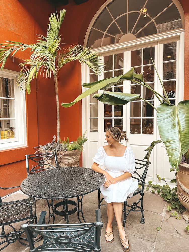 A woman in a white dress sitting in a courtyard in New Orleans.