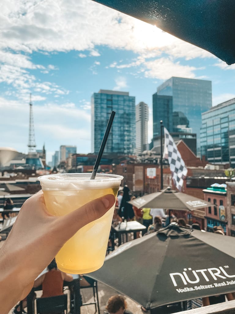 A margarita in front of the skyline in Nashville on a sunny day.