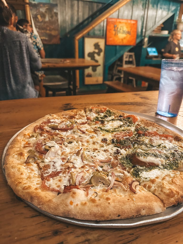 A flatbread pizza is sitting on a wooden table at a local pizza joint in Maui.