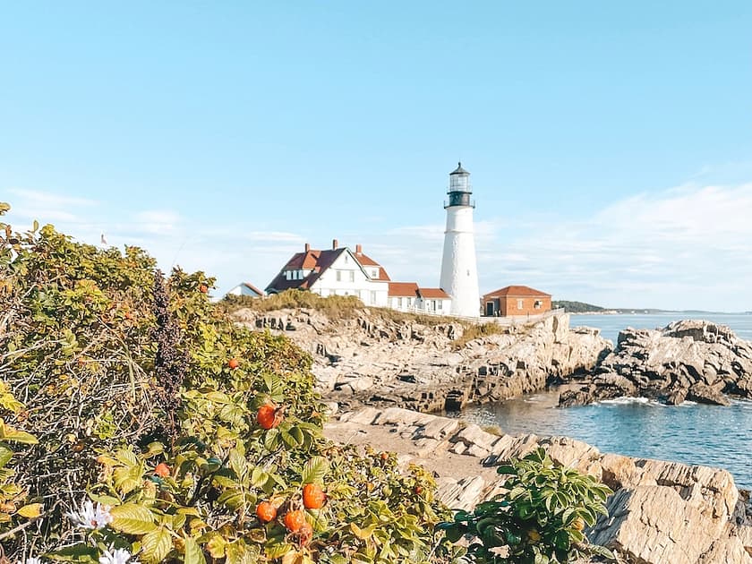 The Portland Head Lighthouse sitting along the rocky coastline in Portland, Maine - one of the best places to visit in the USA in August