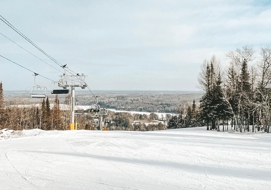 A ski slope with trees, snow, and mountains in the background