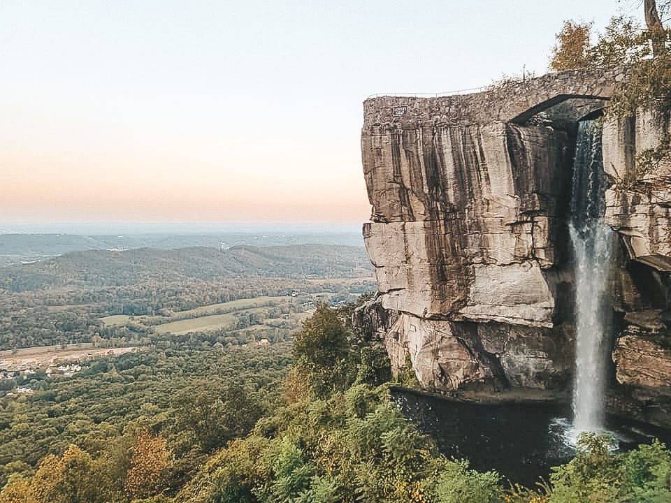 A waterfall falling off a cliff into a forest in Chattanooga: one of the best day trips from Nashville
