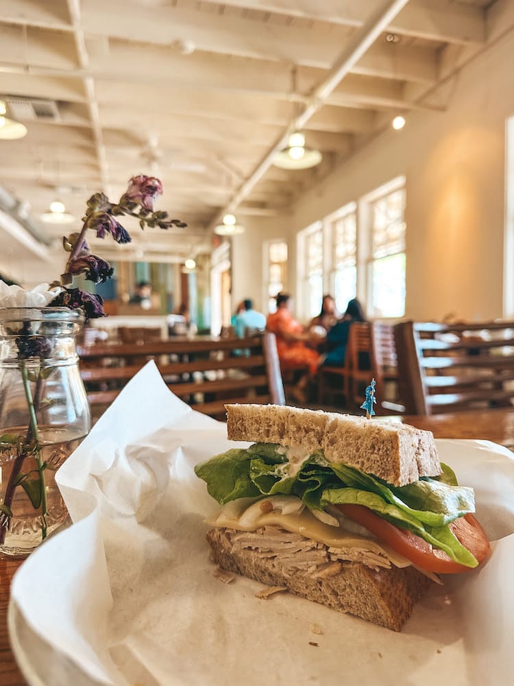 Half of a sandwich stuffed with turkey, cheese, lettuce, and tomato is sitting in a bowl in a restaurant in Maui.