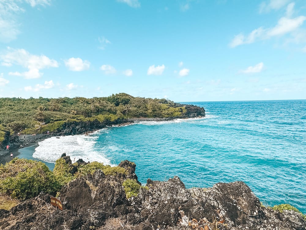 The turquoise ocean, black rocks, and green foliage at Waiʻānapanapa State Park in Maui.