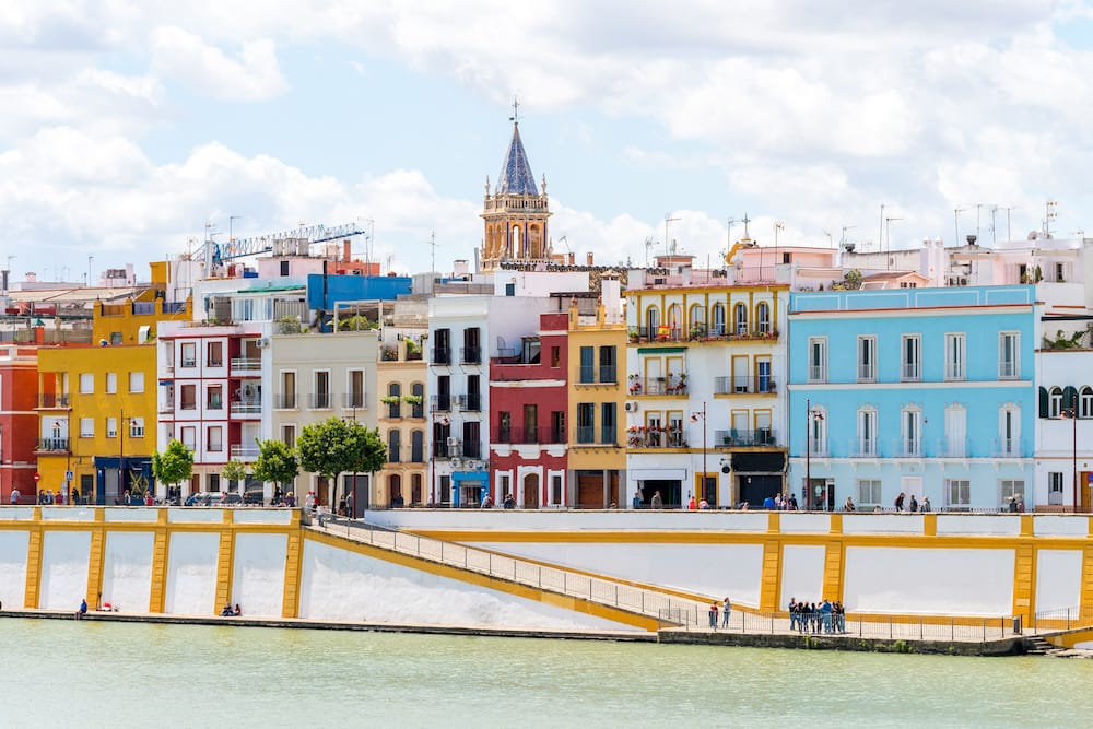 Several colorful buildings against a waterway in Seville.